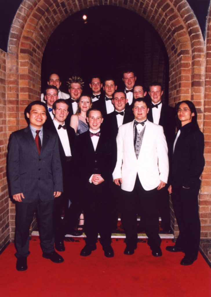 The JCR Committee in formal dress under an archway inside Kelham Hall Ballroom.