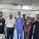 Oliver Cujic in medical scrubs with other hospital staff.